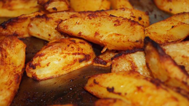 Golden-brown roasted potato pieces with crisp edges on a baking tray.