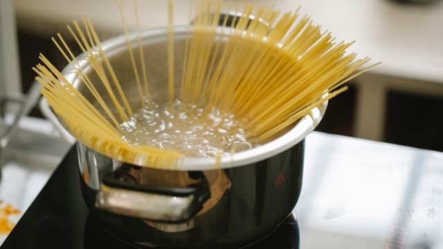 Spaghetti cooking in a pot of boiling water on a stovetop.
